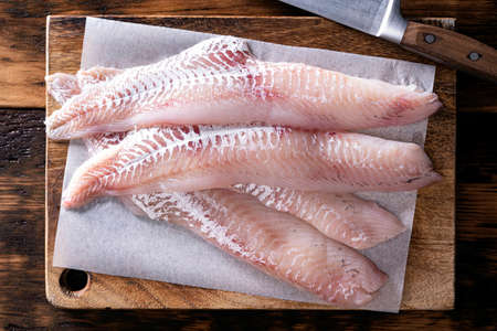 Fresh haddock fillets on a wooden cutting board.