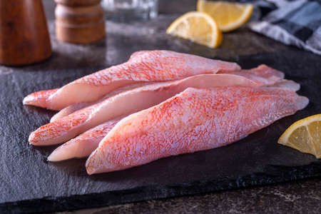 Fresh ocean perch Acadian redfish fillets on a slate board.
