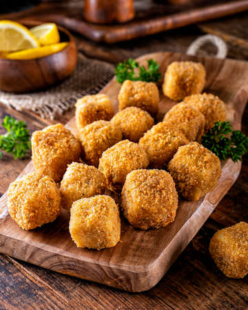 Delicious breaded fish nugget snacks on a rustic wood table top.の写真素材