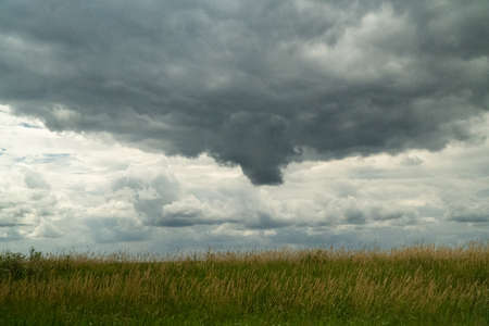dark storm clouds rolling in across farm fieldの写真素材