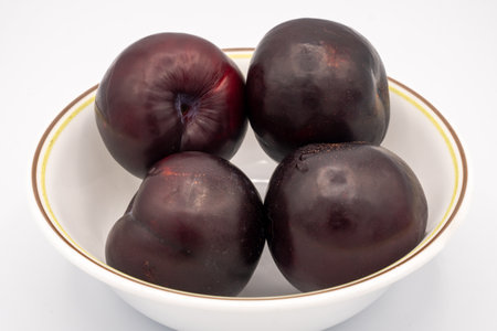 Plums in a bowl on a white backgroundの写真素材
