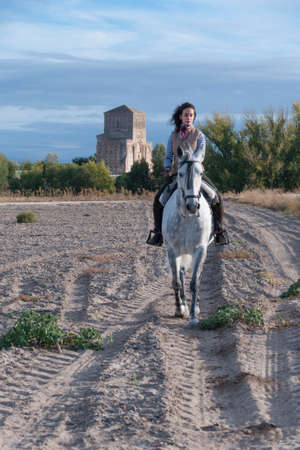 young woman with handkerchief and long hair riding a horseの写真素材