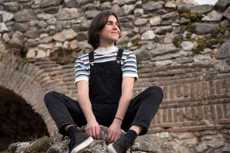Young man posing in the field and with a bridge in the background. Enjoying the outdoors