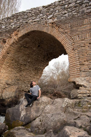 Young man posing in the field and with a bridge in the background. Enjoying the outdoorsの写真素材