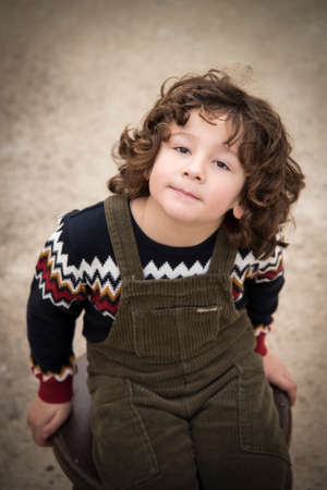 little boy with curly hair and without a tooth posing with a green bibの写真素材