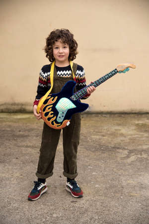 boy playing and experimenting with a toy guitar with striking colorsの写真素材