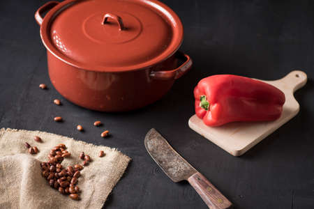 table with black beans on a piece of esparto and next to a casserole and a red pepperの写真素材