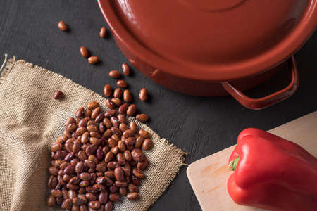 table with black beans on a piece of esparto and next to a casserole and a red pepperの写真素材