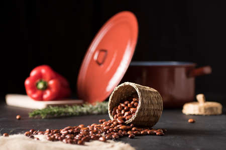 table with black beans in a wicker bowl and on a piece of esparto, next to a casserole and a red...