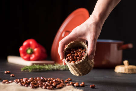 table with black beans in a wicker bowl and on a piece of esparto, next to a casserole and a red pepperの写真素材