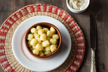 Delicious dish of round potato gnocchi accompanied by cheese sauce with the necessary accessories to taste themの写真素材