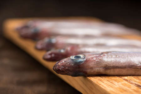 Blue whiting or lilies, fish on the table prepared to be cleaned and cooked in different ways,...
