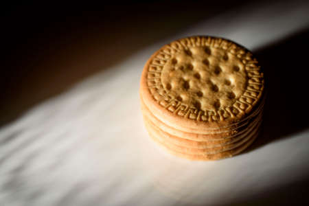 pile of round cookies on a white surface, illuminated with a circle of lightの写真素材