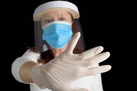 Forgive partially covering the face in which she wears a protective mask, with one hand, with a...