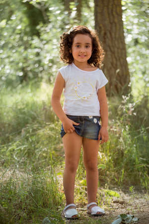 Girl in white t-shirt and denim miniskirt posing inside a grove.の写真素材