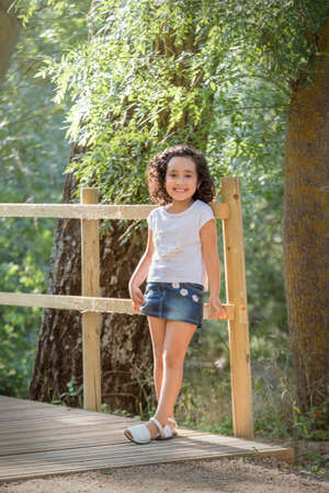 Girl in white t-shirt and denim miniskirt posing inside a grove.の写真素材