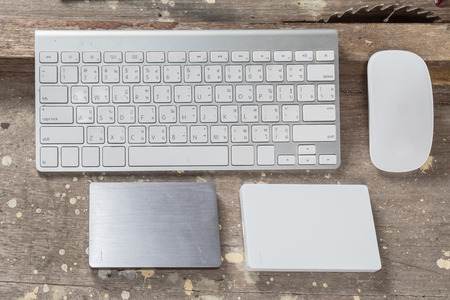 office table with computer keyboard and computer mouse, and external disk, top view