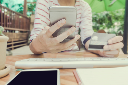 woman using smartphone and computer to online shopping and pay by credit card, Low light, selective focus on hand, can be used for e-commerce, business, technology and internet concept, Vintage toneの写真素材