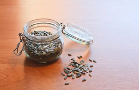 Pumpkin seed on table with open jarの写真素材