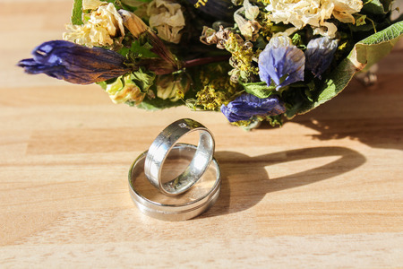 Wedding rings with dry flower on wooden backgroundの写真素材
