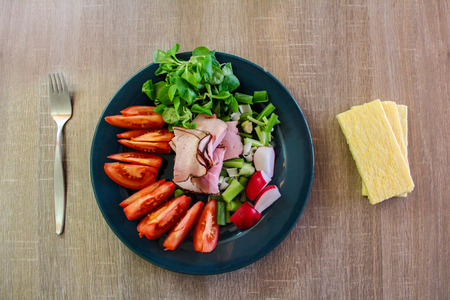 Slice of smoked meat with cracker and vegetable on wooden tableの写真素材