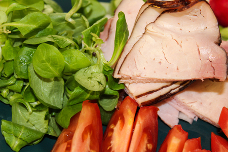 Slice of smoked meat with tomato and herbの写真素材