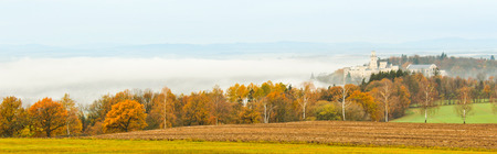 Castle Hluboka nad Vltavou with autumn trees and fog, Czech landscapeのeditorial素材