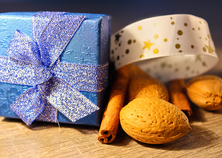 Whole almond, cinnamon and christmas box on wood background