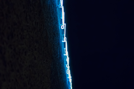 Blue neon light on dark texture wall from bottomの写真素材