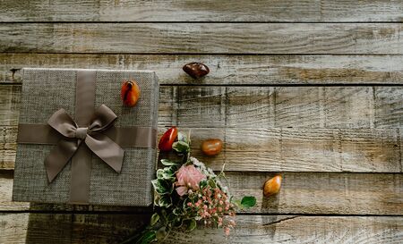 Flower bouquet with gift box and stone on wood background from top. Can be used for wedding, mother day, valentineの写真素材