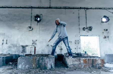 Portrait of a handsome caucasian hip hop dancer, freestyling outdoors in an old abandoned building, blue tonedの写真素材