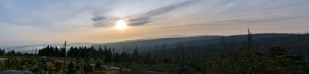 Panoramic sunrise with trees, distant hill and fog on Tristolicnik. Sumava National Park and...
