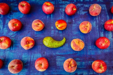 Apple with nectarine, peach and pear in rows on blue background, raw healhy food conceptの写真素材