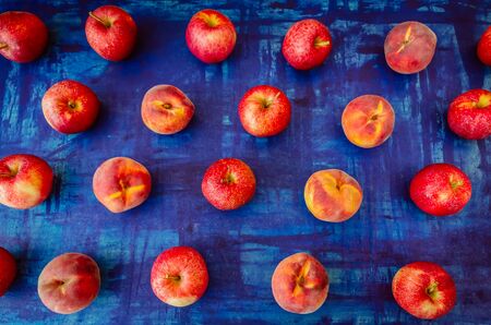 Apple with peach in rows on blue background, raw healhy food conceptの写真素材
