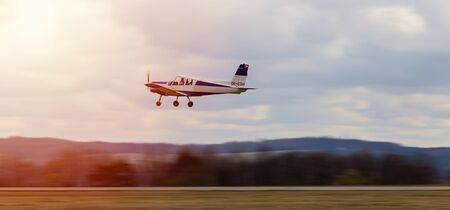 Ultralight plane take off from runway on airports with cloud sky and sun. Panning photoの写真素材