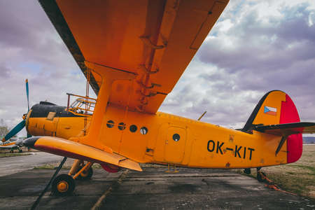 Yellow biplane from side standing on airports with cloud skyのeditorial素材