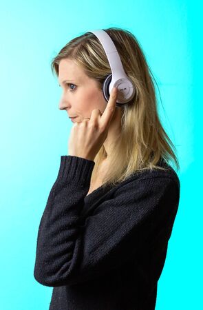 Portrait of beauty young caucasian blonde hair woman listen music on headphone on blue background....