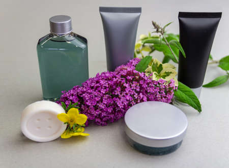 Black, silver tube, clear water bottle, creame box and soap with flower on cartoon desk. Product...