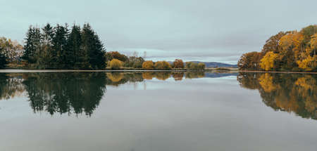 Autumn tree foliage reflection on pond edge. Czech toned landscape