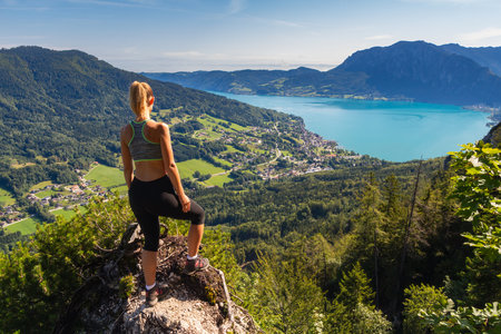 Young caucasian woman standing on lookout Sankt Gilgen near hill Schafberg with Attersee, Austriaの写真素材