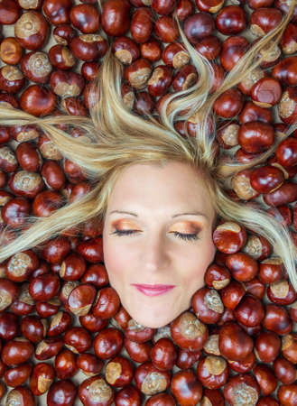 Portrait, head of young beauty caucasian woman with blonde hair and closed eye in chestnut background. Autumn, cosmetics conceptの写真素材