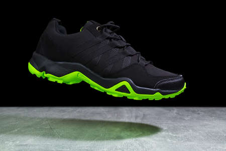 Flying touristic waterproof black and green man shoe from side on marble backgroundの写真素材