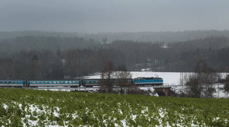 Train running on rails through winter Czech landscape with snow and fog, moody weather. Transportation conceptの写真素材