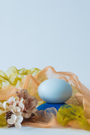 Pastel colored net with flower decoration and blue stone for product placement. Cosmetics backgroundの写真素材