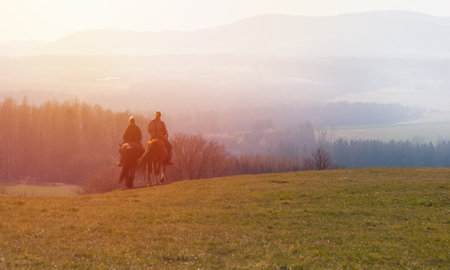 Man and woman, pair riding on horse in morning misty fog with sunrise. Romantic, realax hobby backgroundの写真素材