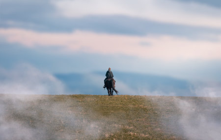 Woman riding on horse in morning misty fog with sunrise. Romantic, realax hobby backgroundの素材 [FY310205859632]