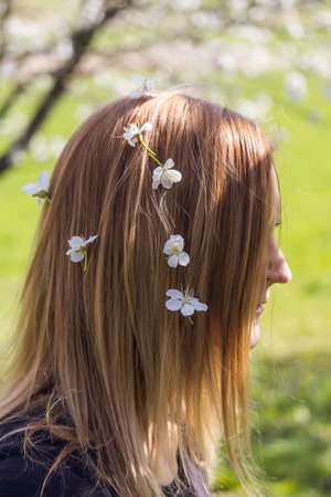 Portrait of young beauty Caucasian woman from side with cherry blossom in her hair. People, spring conceptの写真素材