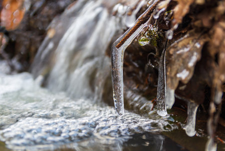 Close up detail of frozen branch in small waterfall, brook. Thawing, weather, early spring backgroundの写真素材