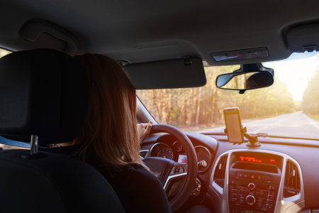 Young woman driving inside car on forest road with navigation. Transportation, road on vacation...