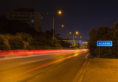 Alanya sign with car light trail on road. Turkey traffic, travel background